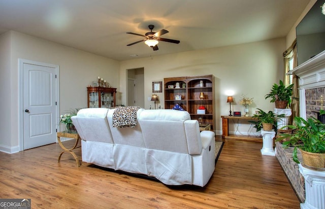 living room with a brick fireplace, ceiling fan, and hardwood / wood-style flooring