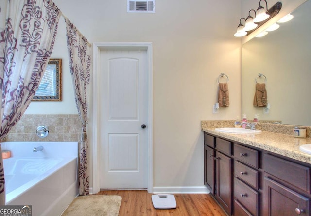 bathroom featuring hardwood / wood-style flooring, vanity, and a washtub