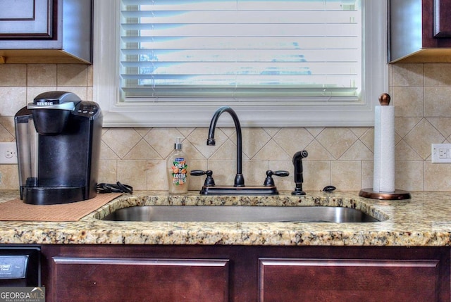 interior details with decorative backsplash, light stone countertops, and sink