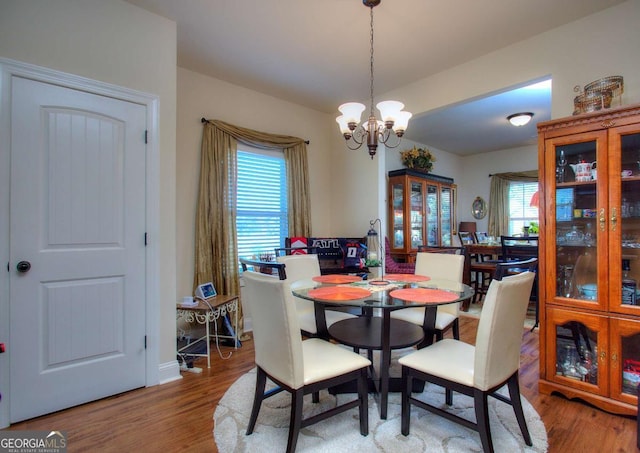 dining area with wood-type flooring and a chandelier