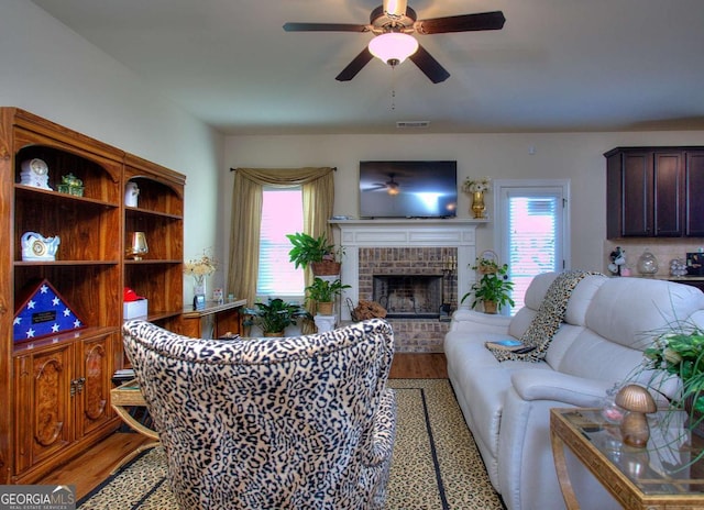 living room featuring a fireplace, wood-type flooring, a wealth of natural light, and ceiling fan