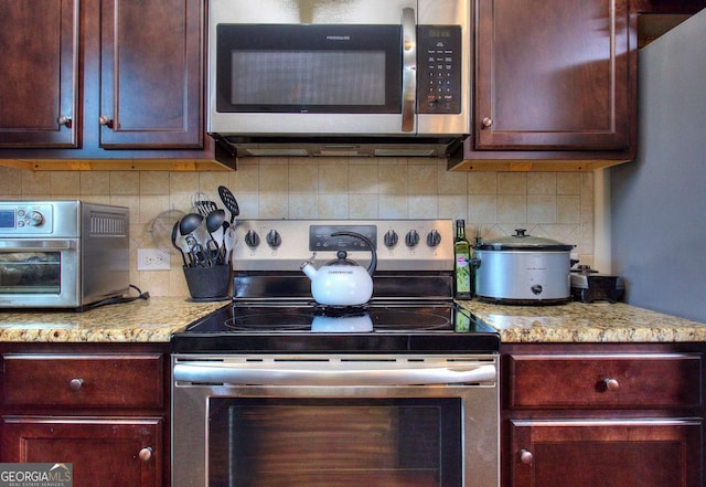 kitchen with light stone countertops, stainless steel appliances, and tasteful backsplash