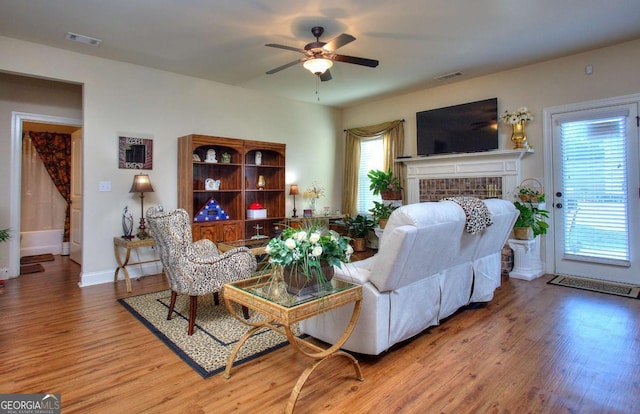 living room featuring hardwood / wood-style floors, ceiling fan, a healthy amount of sunlight, and a brick fireplace