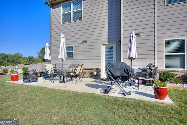 back of property featuring a yard, a patio, and a fire pit