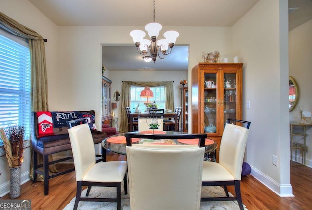 dining area with wood-type flooring and an inviting chandelier