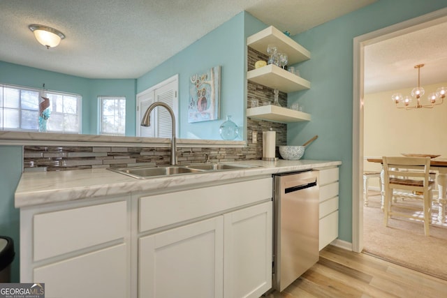 kitchen with light stone counters, sink, white cabinetry, stainless steel dishwasher, and tasteful backsplash