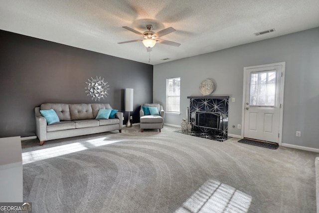 unfurnished living room with a high end fireplace, a textured ceiling, ceiling fan, and carpet flooring