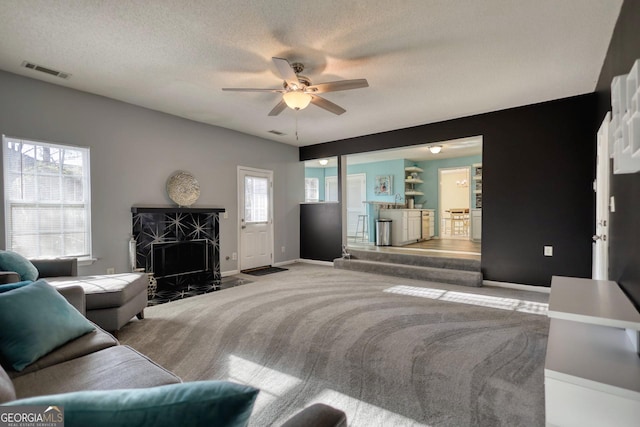 living room with a premium fireplace, ceiling fan, carpet flooring, and plenty of natural light