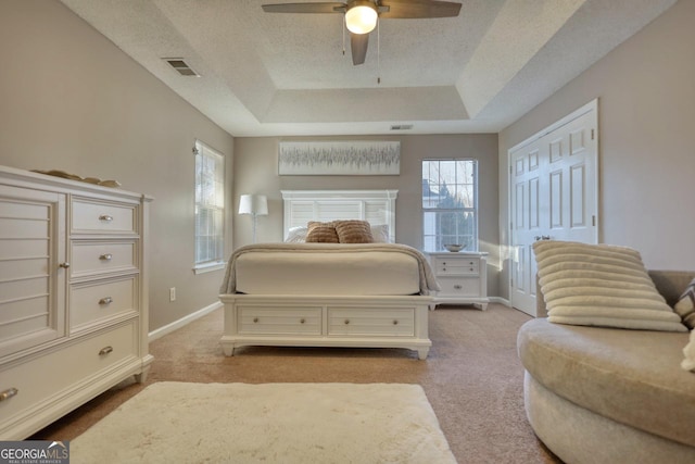 bedroom featuring a closet, a raised ceiling, ceiling fan, and light carpet