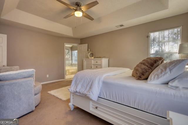 bedroom featuring connected bathroom, a raised ceiling, carpet floors, and ceiling fan