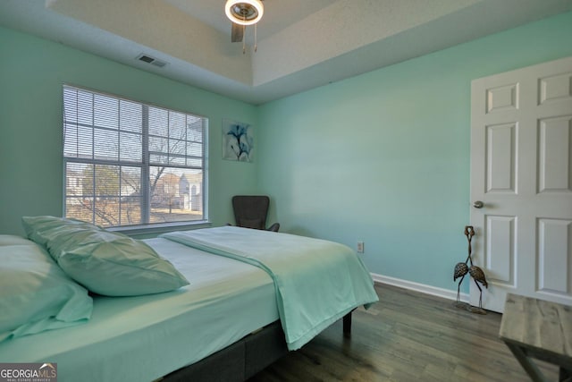 bedroom featuring hardwood / wood-style flooring, ceiling fan, and a tray ceiling