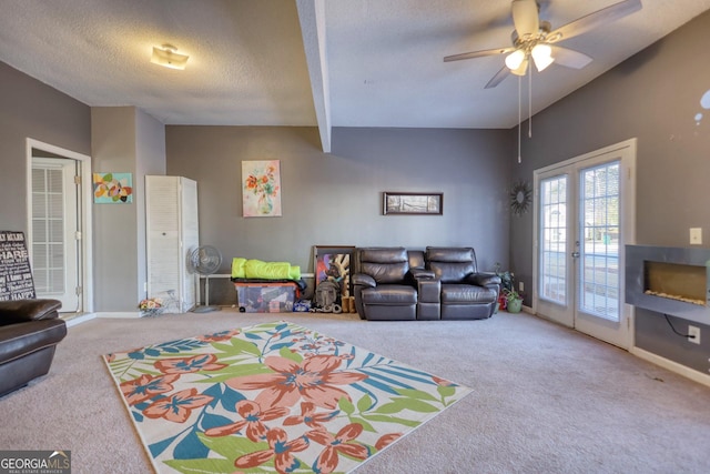 living room featuring a textured ceiling, beamed ceiling, french doors, ceiling fan, and carpet floors