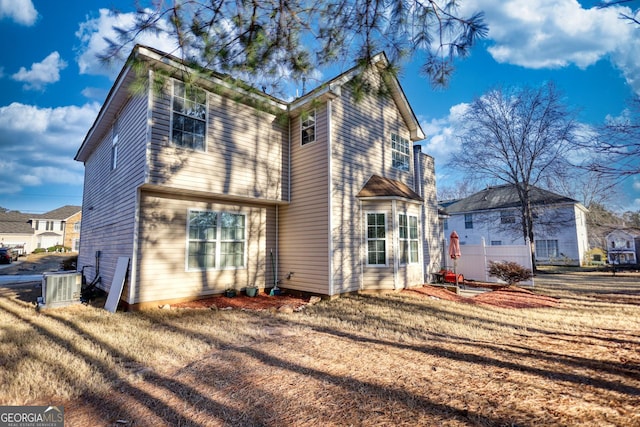 back of property with central AC unit and a yard