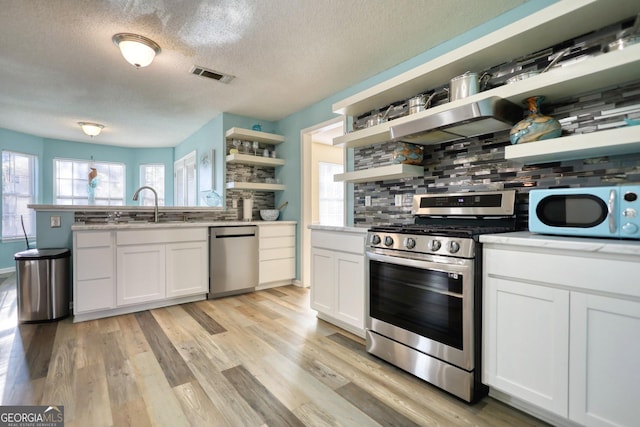 kitchen featuring a textured ceiling, stainless steel appliances, tasteful backsplash, white cabinetry, and sink