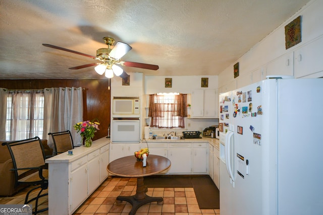 kitchen featuring white appliances, tile patterned floors, a textured ceiling, and white cabinets