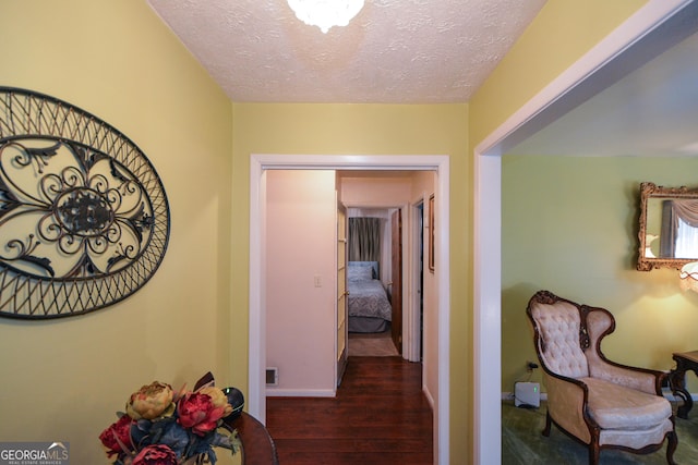 corridor with dark hardwood / wood-style flooring and a textured ceiling