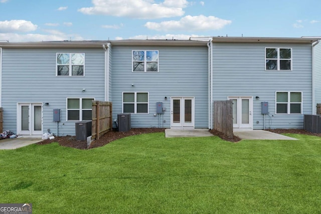 rear view of property with cooling unit, a patio area, and a yard