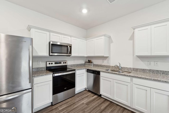 kitchen featuring white cabinets, sink, dark hardwood / wood-style floors, light stone countertops, and appliances with stainless steel finishes