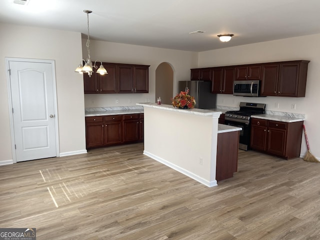 kitchen with light wood finished floors, arched walkways, stainless steel appliances, light countertops, and a chandelier