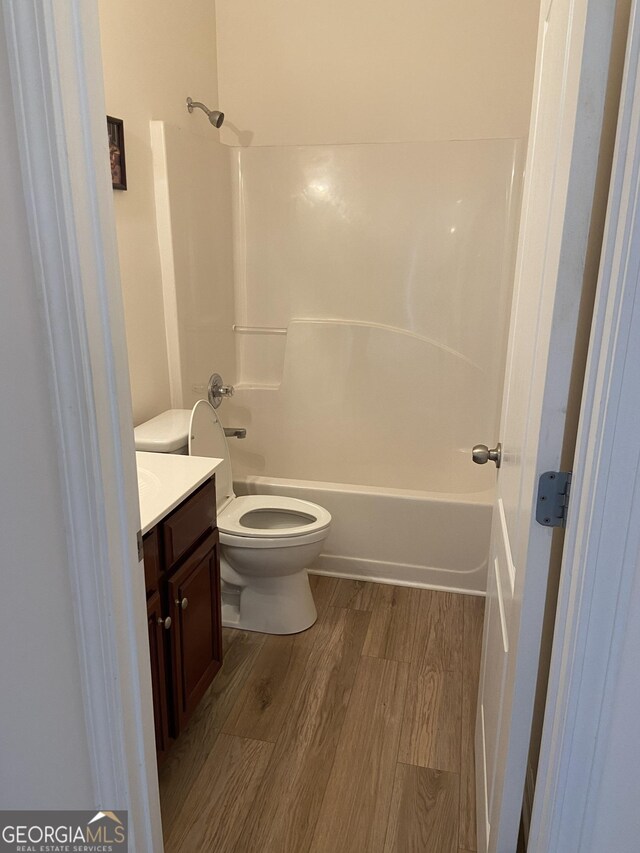 full bathroom with toilet, hardwood / wood-style flooring, vanity, and bathtub / shower combination