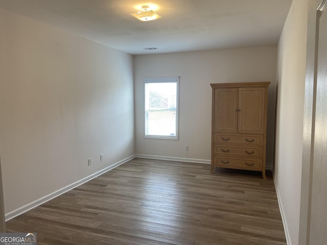 unfurnished bedroom featuring dark wood-type flooring, visible vents, and baseboards