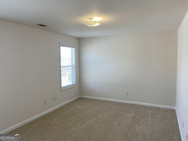 carpeted spare room featuring visible vents and baseboards