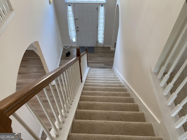 staircase with baseboards and arched walkways