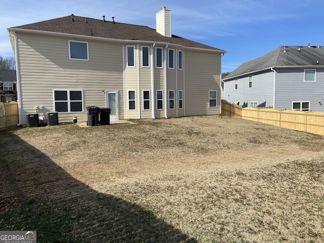 rear view of house featuring a chimney, fence, and cooling unit