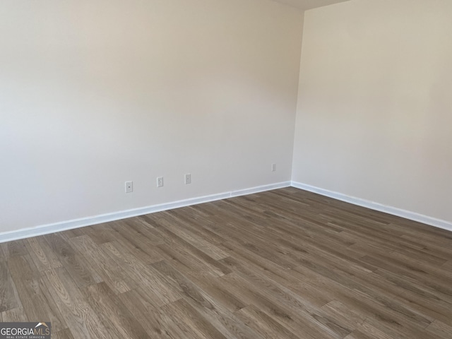 empty room with dark wood-style floors and baseboards