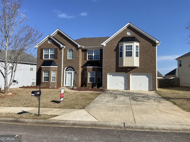 view of front facade with driveway, brick siding, an attached garage, and fence