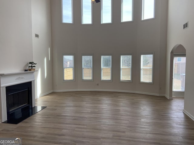 unfurnished living room with a high ceiling, ceiling fan, and hardwood / wood-style floors