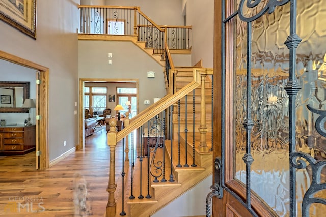 stairs featuring wood-type flooring and a high ceiling