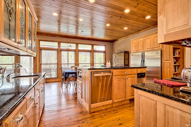 kitchen with appliances with stainless steel finishes, light hardwood / wood-style floors, dark stone countertops, and sink