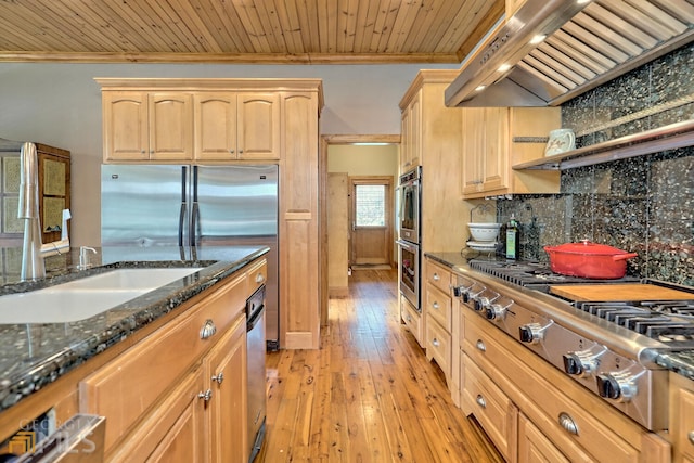 kitchen with decorative backsplash, appliances with stainless steel finishes, wall chimney exhaust hood, wood ceiling, and light brown cabinets