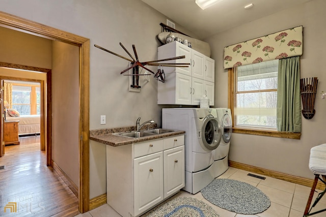 laundry area with washer and clothes dryer, cabinets, light tile patterned floors, and sink