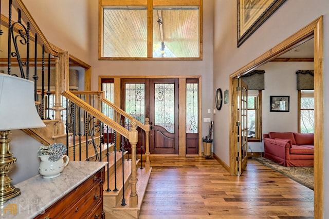 entryway with wood-type flooring, french doors, and a high ceiling