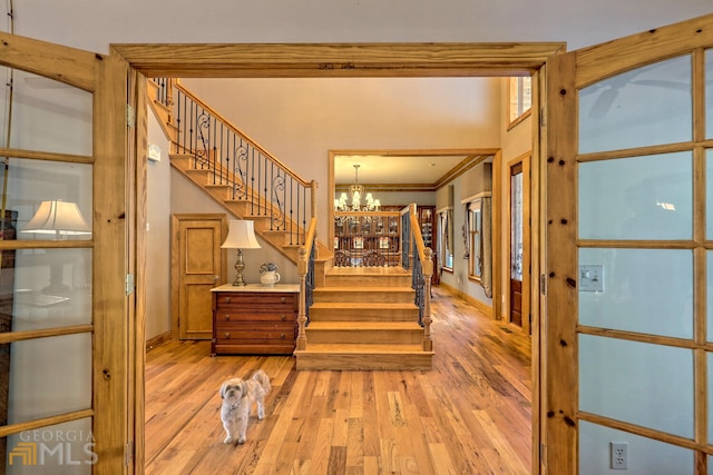 stairway featuring ornamental molding, wood-type flooring, and an inviting chandelier