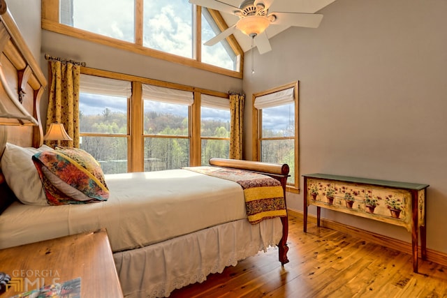 bedroom with hardwood / wood-style floors, a towering ceiling, and ceiling fan