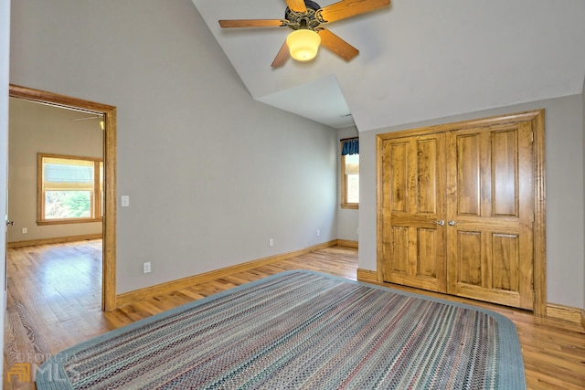 unfurnished bedroom featuring ceiling fan, light hardwood / wood-style floors, lofted ceiling, and a closet