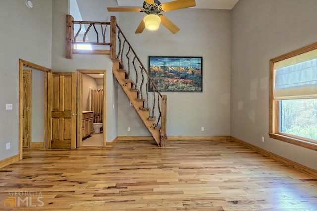 unfurnished living room with a high ceiling, light hardwood / wood-style flooring, and ceiling fan