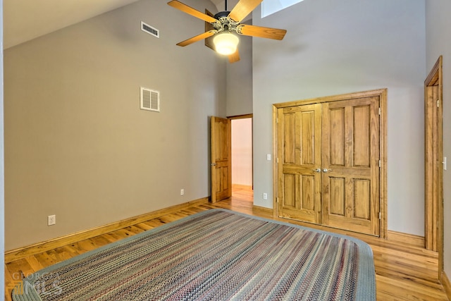 unfurnished bedroom with ceiling fan, high vaulted ceiling, and light hardwood / wood-style flooring