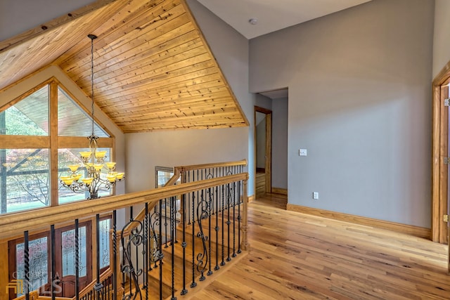 hallway with wooden ceiling, high vaulted ceiling, a chandelier, and light hardwood / wood-style floors