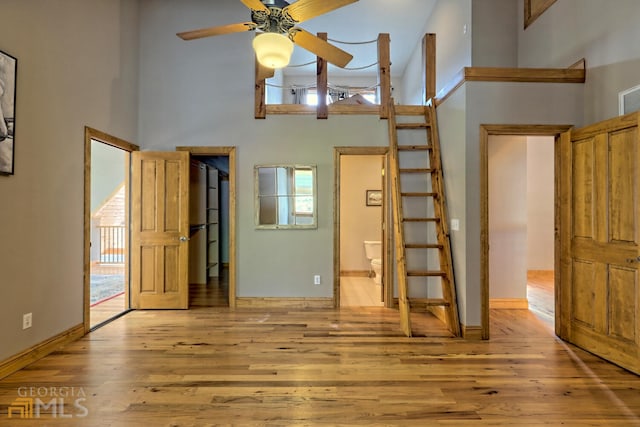 interior space featuring ceiling fan, a towering ceiling, and light hardwood / wood-style flooring