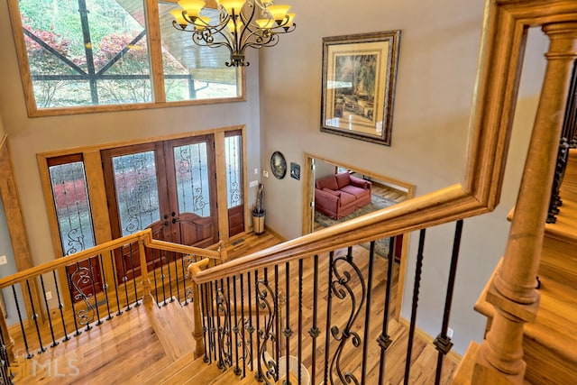 entryway with a notable chandelier, a towering ceiling, parquet floors, and french doors