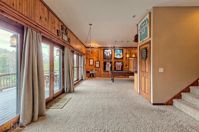 interior space with plenty of natural light, wood walls, light colored carpet, and french doors