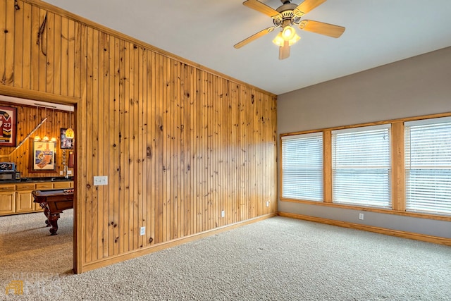 spare room featuring carpet flooring, ceiling fan, wood walls, and billiards