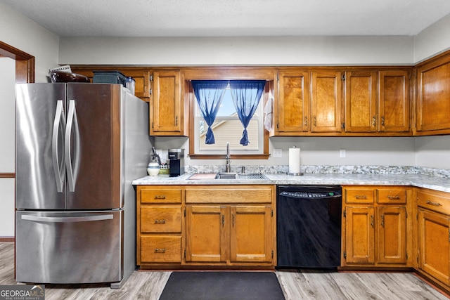 kitchen with dishwasher, sink, stainless steel refrigerator, and light hardwood / wood-style flooring