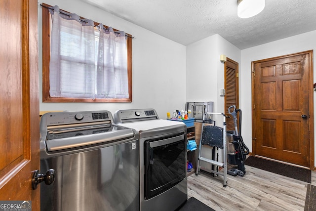 washroom featuring separate washer and dryer, a textured ceiling, and light hardwood / wood-style flooring