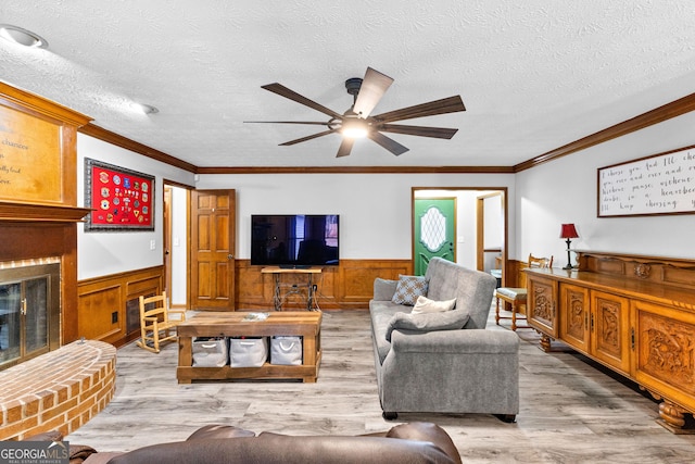 living room featuring a fireplace, light wood-type flooring, a textured ceiling, and crown molding