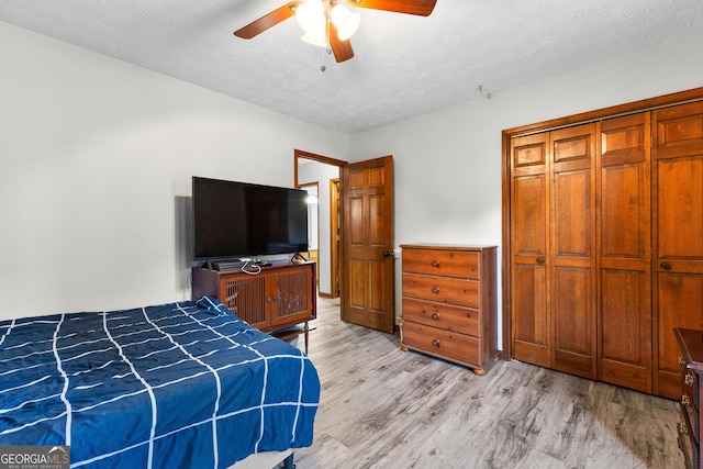 bedroom featuring a textured ceiling, a closet, ceiling fan, and light hardwood / wood-style floors